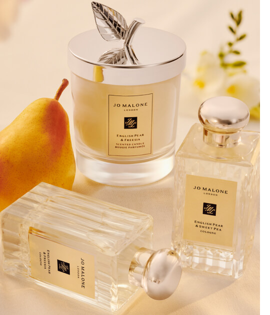 English Pear and Freesia colognes and candle on a table with a pear